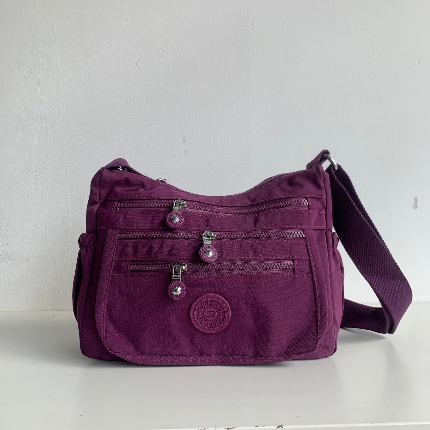 GESSY FRONT TRIPLE ZIP NYLON CROSSBODY BAG IN PURPLE